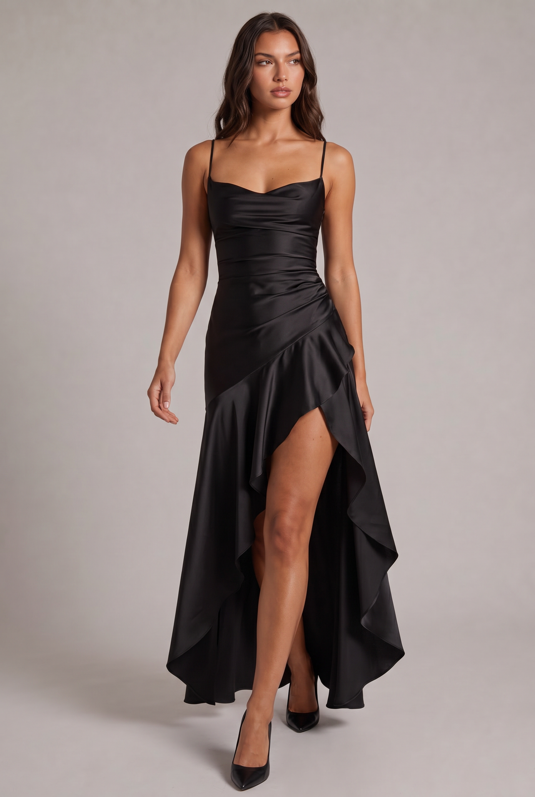 Schwarzes Satin-Maxikleid mit Spaghettiträgern und asymmetrischem Volant mit Beinschlitz, beim Gehen frontal fotografiert, dazu schwarze Pumps. 9