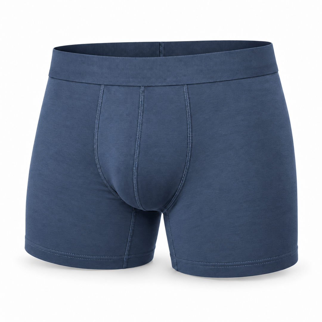 Einzelne blaugraue Boxershorts in der Vorderansicht mit breitem Bund und Ziernähten vor weißem Hintergrund. 9
