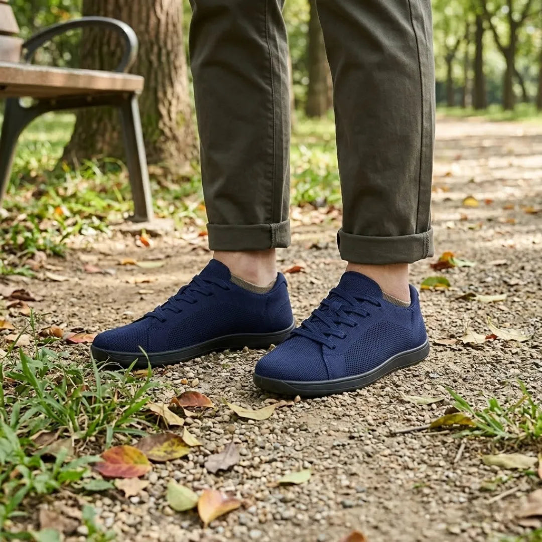 Marineblaue Sneaker mit schwarzer Sohle getragen im Park, dazu olivgrüne Hose, Parkbank, Kies und Laub. 20