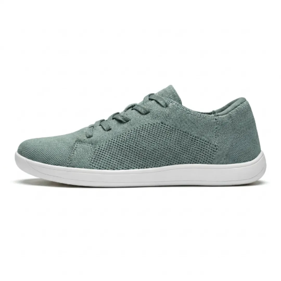 Seitenansicht eines graugrünen Mesh-Sneakers mit weißer flacher Sohle und perforiertem Strickmuster im Mittelfußbereich. 28