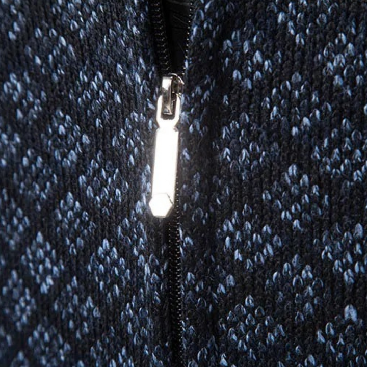 Nahaufnahme eines blauen Strickstoffs mit silbernem Reißverschluss, geometrisches Muster.
