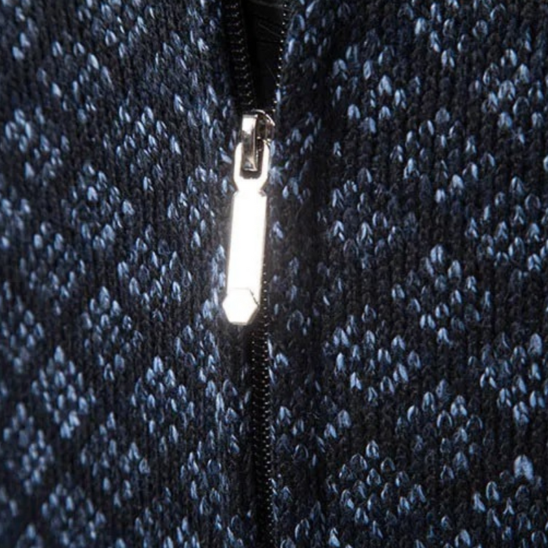 Nahaufnahme eines blauen Strickstoffs mit silbernem Reißverschluss, geometrisches Muster.