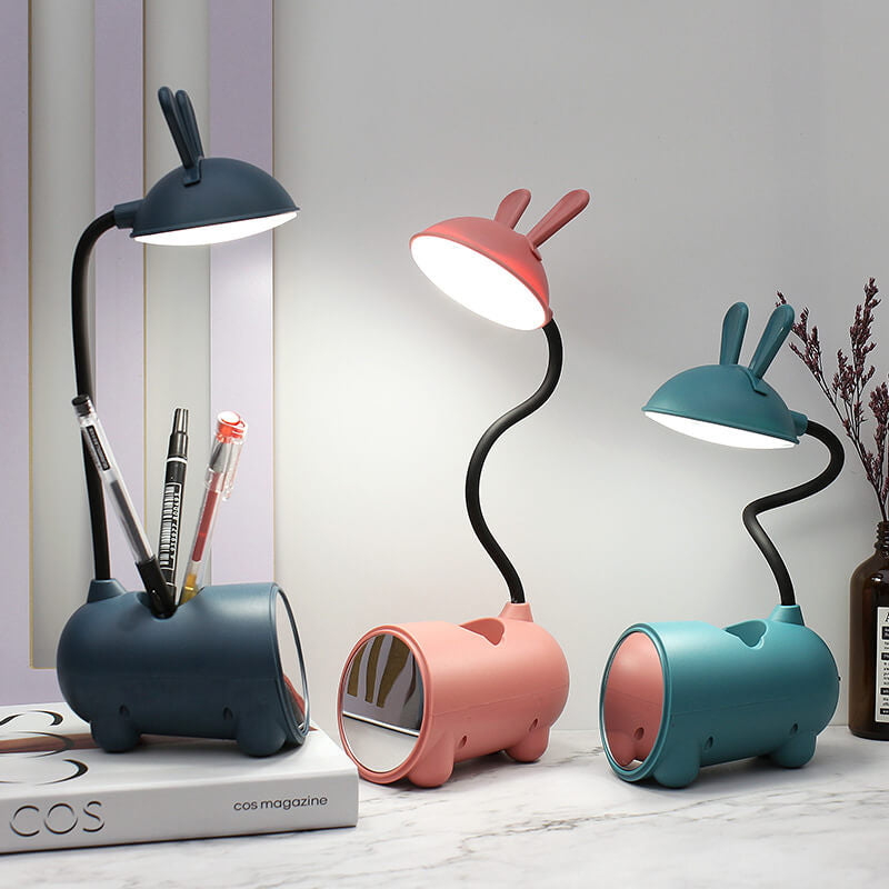 Drei eingeschaltete Hasenlampen in Dunkelblau, Rosa und Grün; die blaue Lampe hält mehrere Stifte im Fach des Sockels. 7
