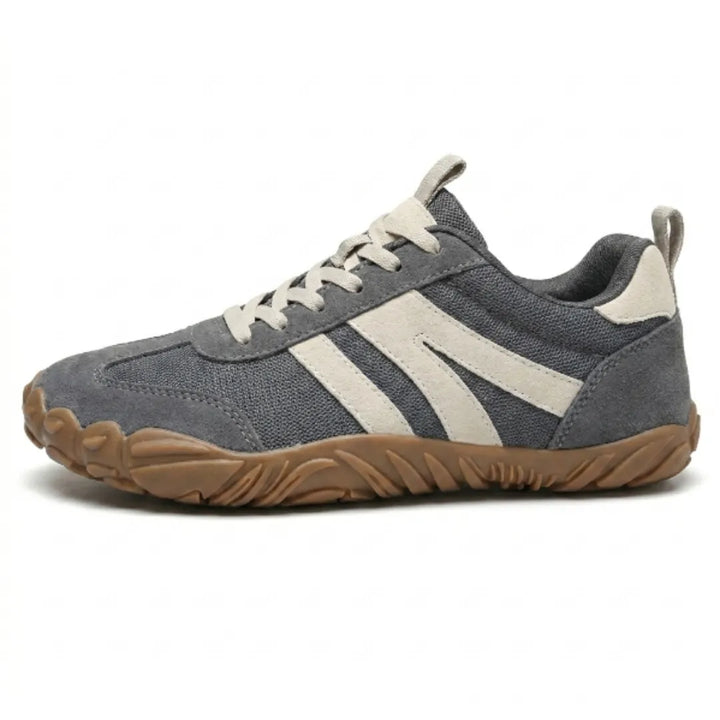 Graue Barfußschuhe mit hellbeigen Seitenstreifen und Schnürung in der Seitenansicht, Mesh-Obermaterial mit Veloursleder-Akzenten und breiter brauner Sohle. 1