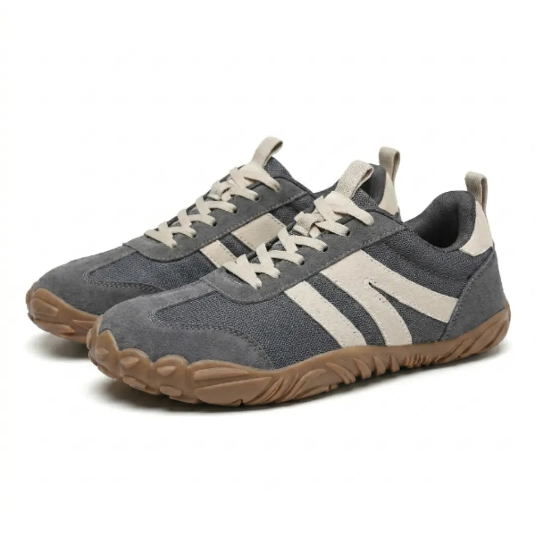 Paar graue Barfußschuhe mit hellbeigen Streifen und Schnürsenkeln schräg von vorne, breite braune Profilsohle sichtbar. 7