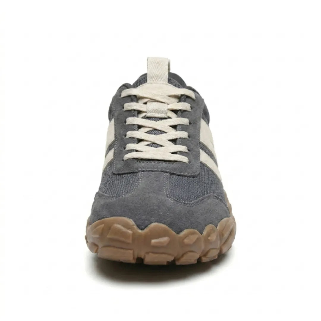 Grauer Barfußschuh frontal fotografiert, die breite Zehenpartie mit gewellter brauner Sohle und die gekreuzte Schnürung sind zu sehen. 8