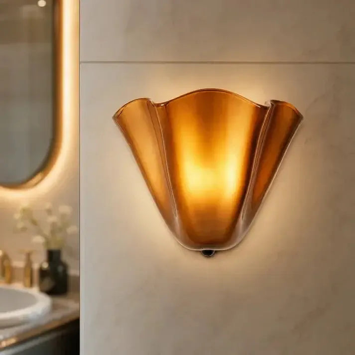 Leuchtende bernsteinfarbene Wandlampe in Nahaufnahme an einer Marmorwand in einem Badezimmer mit beleuchtetem Spiegel. 10