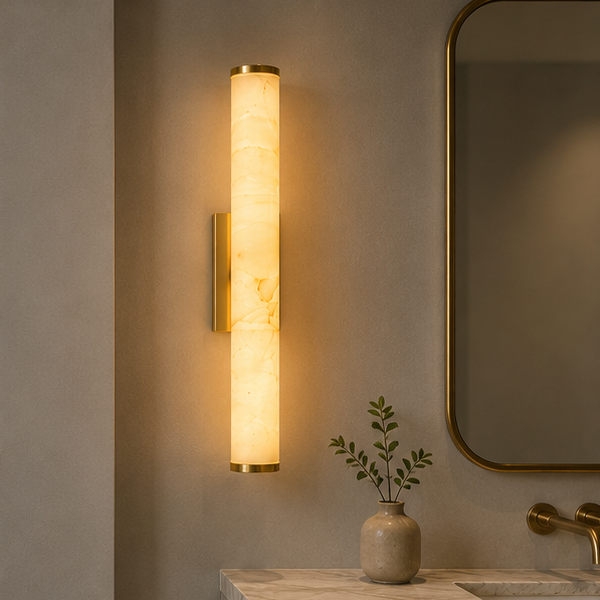 Leuchtende Marmor-Wandleuchte mit goldfarbenen Enden über einem Badezimmer-Waschtisch neben Spiegel, Armatur und einer Vase mit Zweig. 2