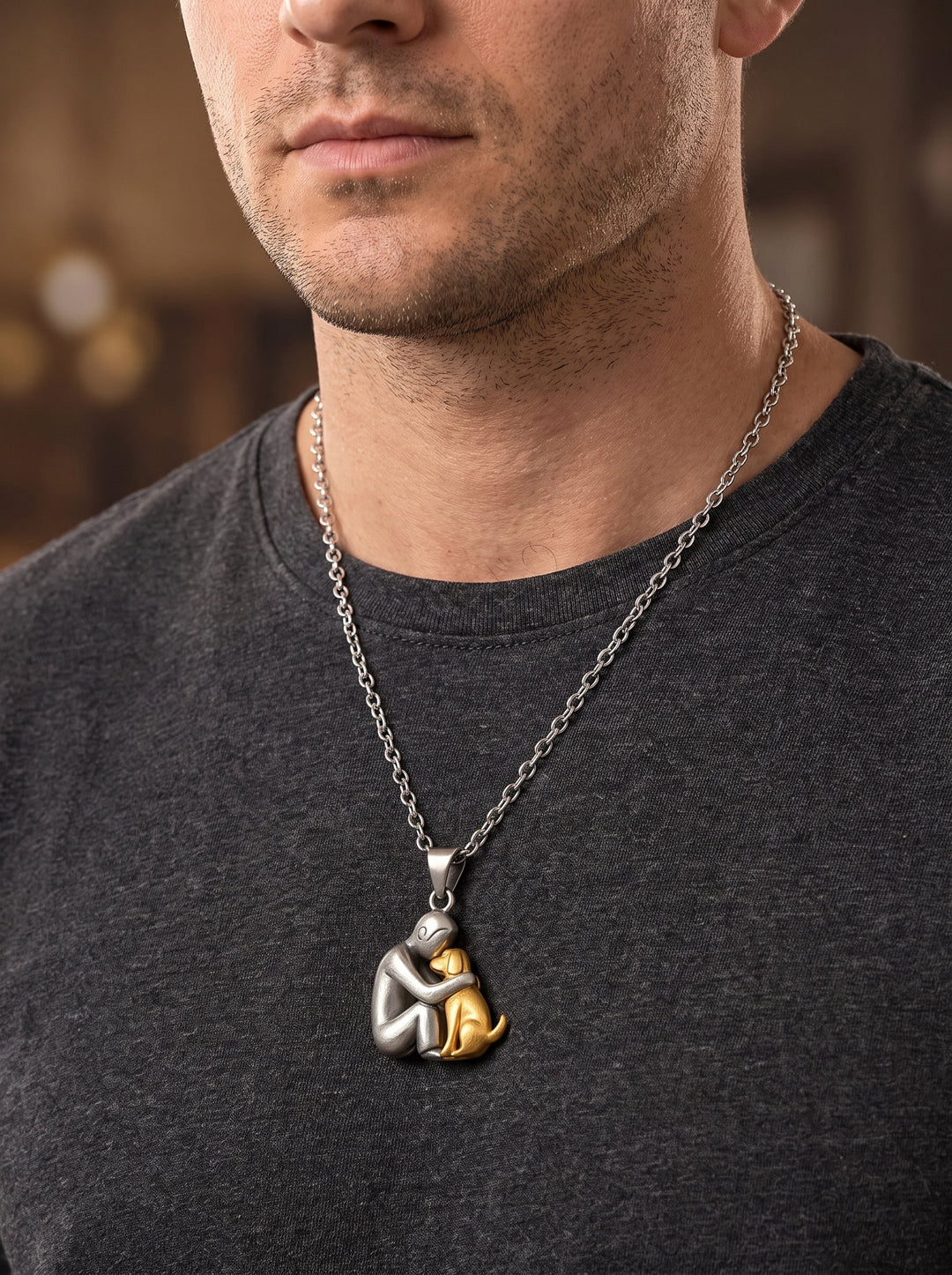 Mann im dunkelgrauen T-Shirt trägt die lange Kette mit mattem Anhänger aus Figur und goldfarbenem Hund. 11