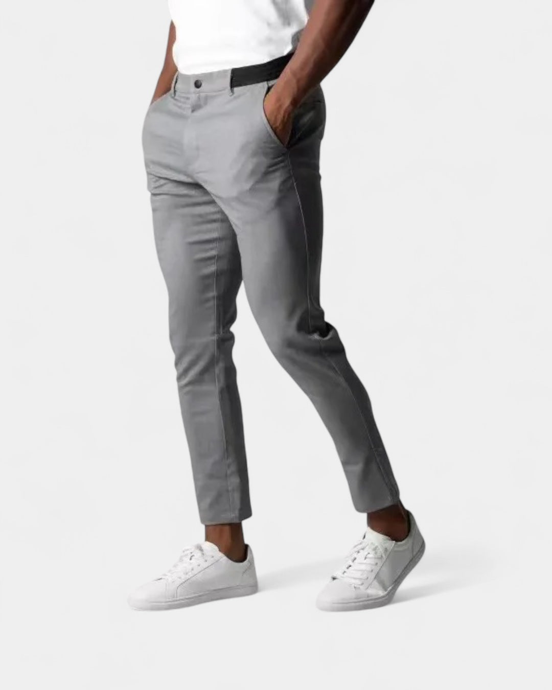 Model in hellgrauer Slim-Hose mit schwarzem Stretchbund, Hände in den Taschen, dazu weiße Sneaker 1
