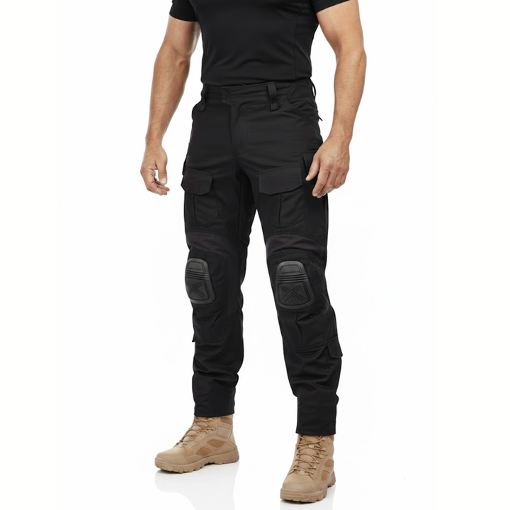 Mann trägt die schwarze Hose mit Knieschonern und Cargotaschen zu schwarzem Shirt und beigen Stiefeln, Frontansicht. 2