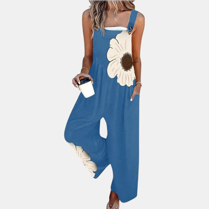 Blaue Latzhose mit großer cremefarbener Blume am Latz, getragen von einem Model mit Kaffeebecher 6