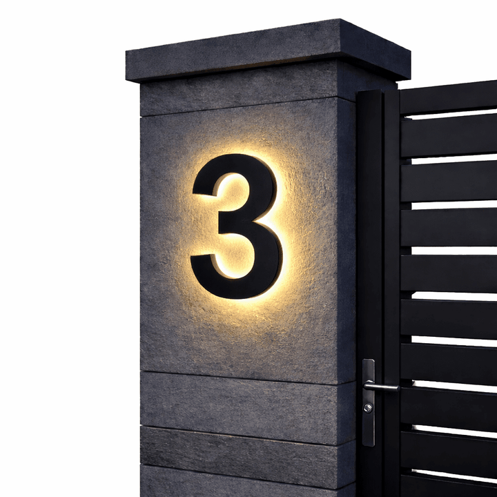 Schwarze Ziffer 3 mit warmem Hintergrundlicht an einem grauen Steinpfeiler vor schwarzem Lamellentor, freigestellt. 9