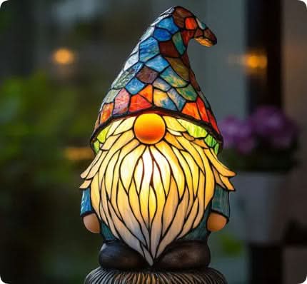 Wichtel-Figur mit buntem Mosaik-Zipfelmütze, langem hell leuchtendem Bart und orangefarbener Nase, vor unscharfem Hintergrund. 13