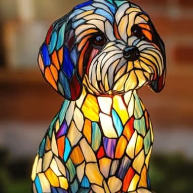 Nahaufnahme einer kleinen Hundefigur mit zotteligem Gesicht und bunten Hängeohren aus Glasmosaik, Ziegelwand im Hintergrund. 17