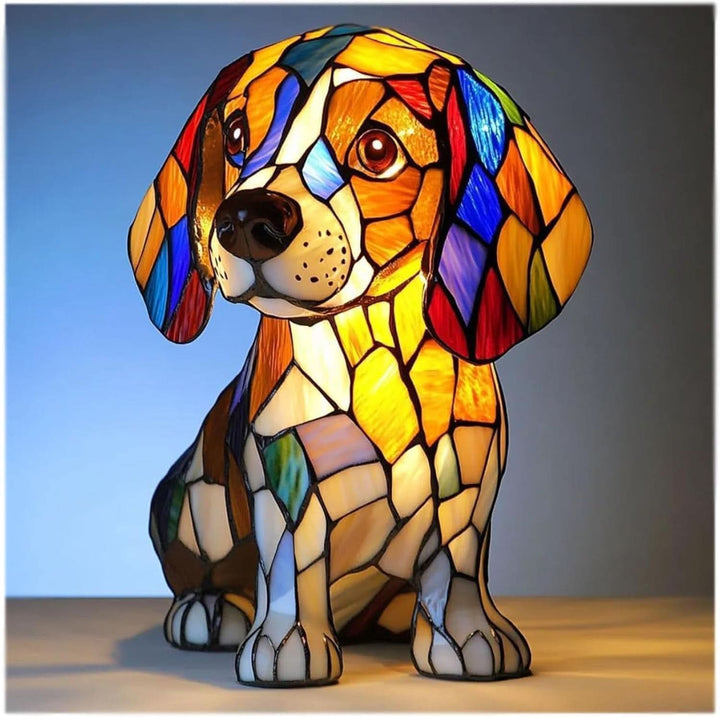 Sitzender Welpe als leuchtende Buntglas-Figur mit Schlappohren in Orange, Blau und Rot, frontal vor blauem Hintergrund. 1
