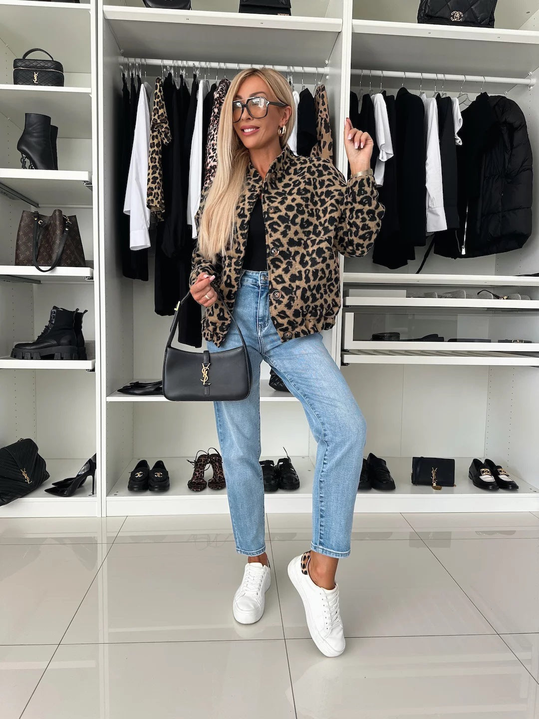 Ganzkörperansicht eines Models in Leopardenjacke, hellblauer Jeans und weißen Sneakern vor einem begehbaren Kleiderschrank. 5
