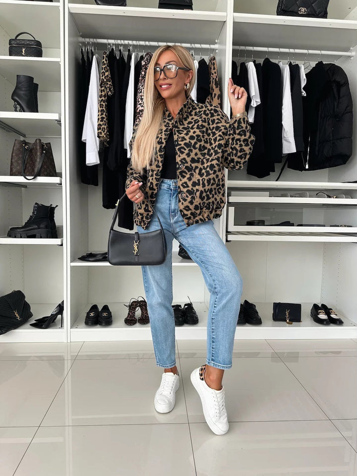 Ganzkörperansicht eines Models in Leopardenjacke, hellblauer Jeans und weißen Sneakern vor einem begehbaren Kleiderschrank. 5