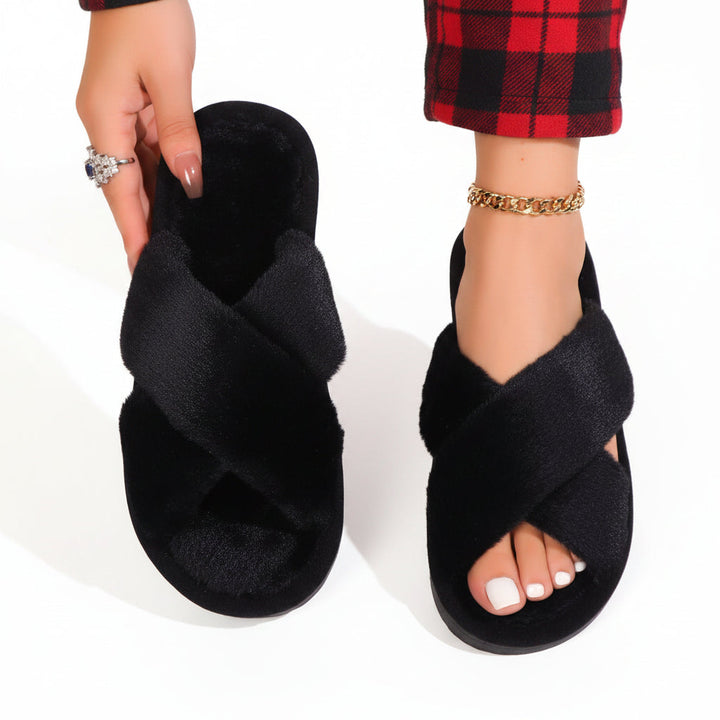 Schwarze Plüsch-Pantoffeln mit gekreuzten Riemen, einer in der Hand gehalten, dazu eine rot-schwarz karierte Hose. 9
