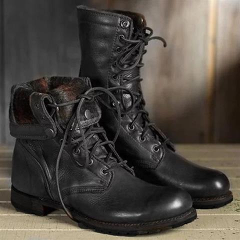 Paar schwarze Schnürstiefel aus glattem Leder, ein Stiefel mit umgeschlagenem, gemustertem Schaftfutter, auf hellem Holzuntergrund. 2