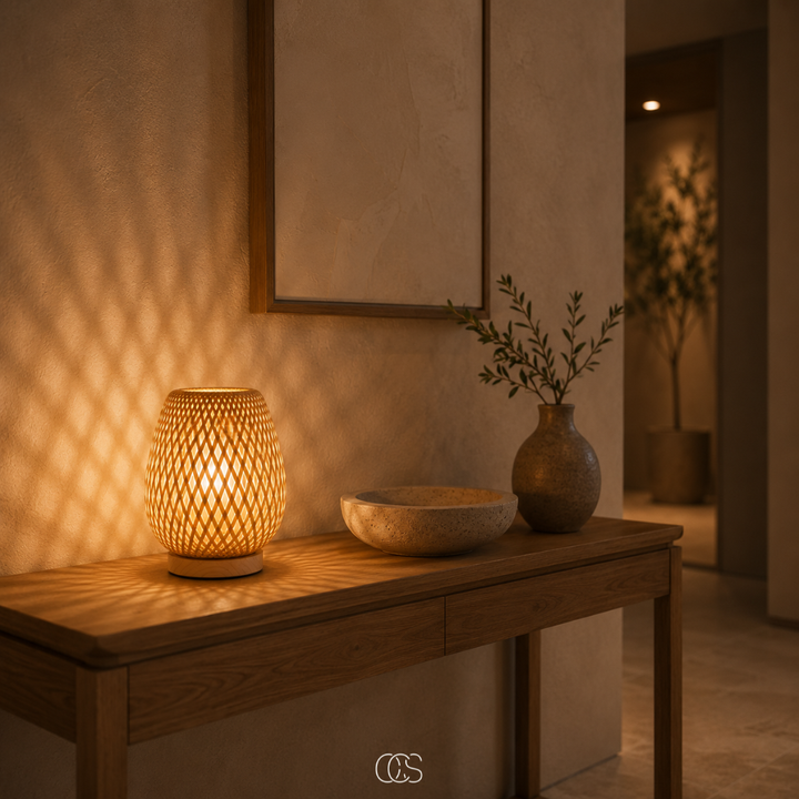 Leuchtende Bambuslampe auf einem Holz-Sideboard im Flur, daneben Steinschale und Vase, Lichtmuster an der Wand. 2
