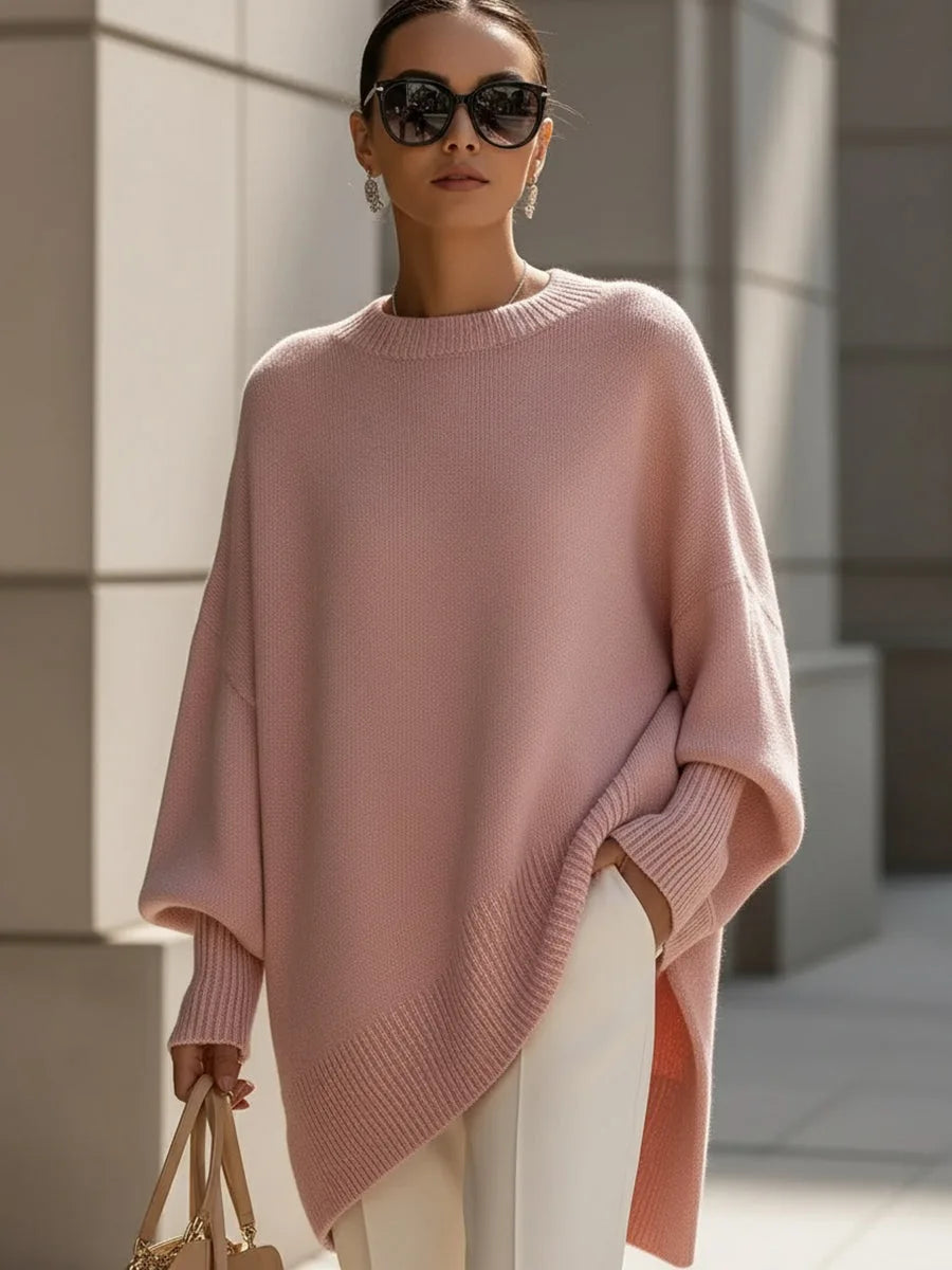 Rosafarbener Oversize-Pullover mit weiten Ärmeln und asymmetrischem Saum, getragen mit weißer Hose, Sonnenbrille und beiger Handtasche. 11