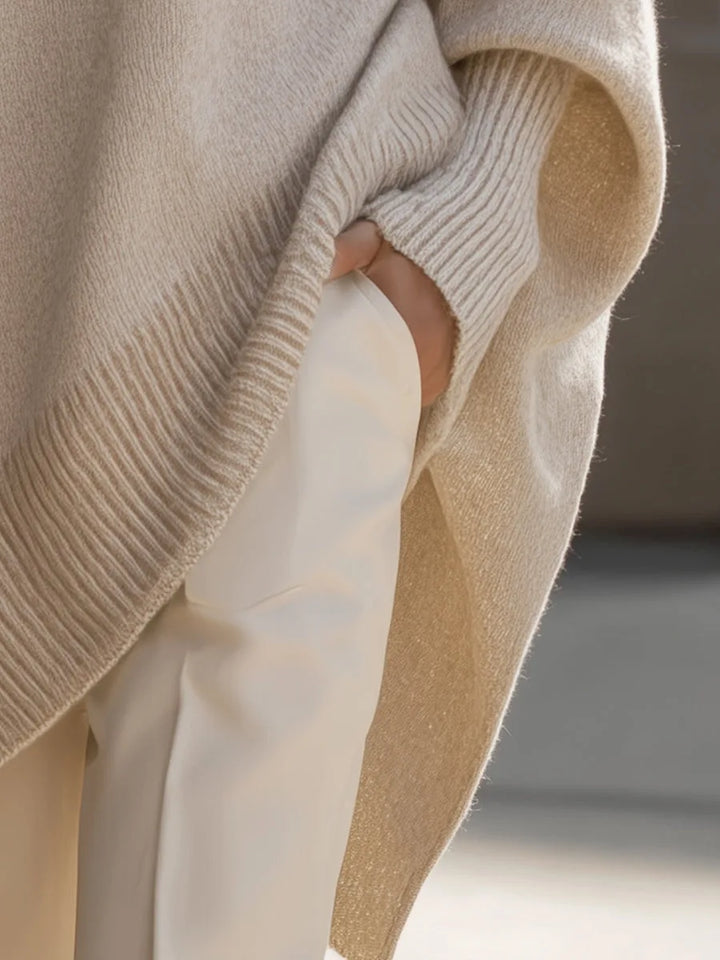 Detail der seitlichen Schlitzpartie des beigen Pullovers mit gerippten Bündchen und leicht glänzender Innenseite, Hand in der Tasche. 5