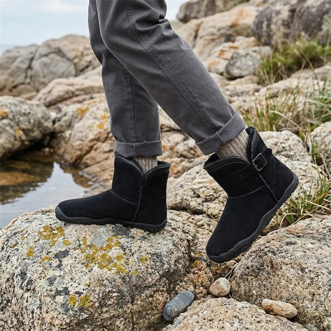 Schwarze Stiefel getragen auf Felsen am Wasser, dazu graue Hose und Wollsocken 11