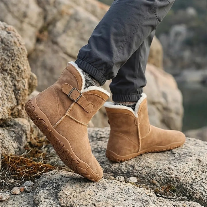 Hellbraune Stiefel mit hellem Fellfutter, getragen auf Felsen, dazu dunkle Hose und gemusterte Socken 20