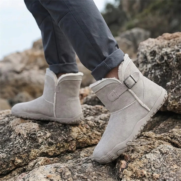Hellgraue Fellstiefel an den Füßen einer Person, die auf felsigem Untergrund mit gekrempelter Jeans steht 29