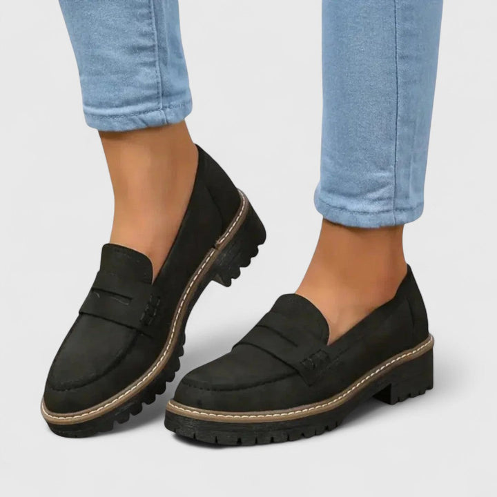 Schwarze Loafer aus Veloursleder-Optik, getragen zu hellblauer Jeans, mit kräftiger Profilsohle und heller Ziernaht 1