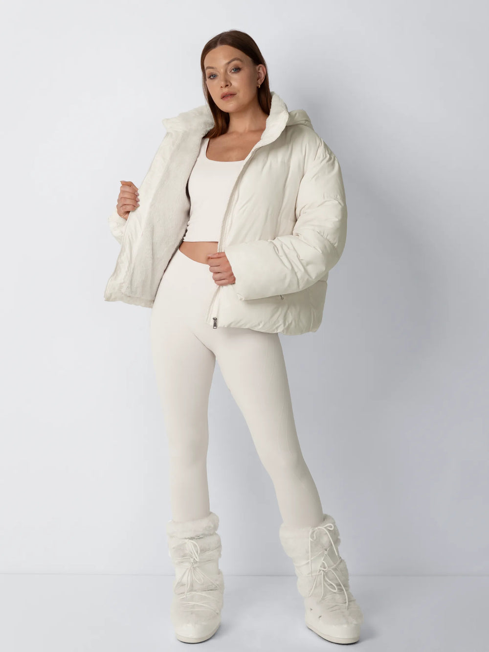 Model in cremeweiĂźer Steppjacke zeigt das weiche Fleecefutter, dazu Leggings und Pelzstiefel im Ganzkörperlook 2
