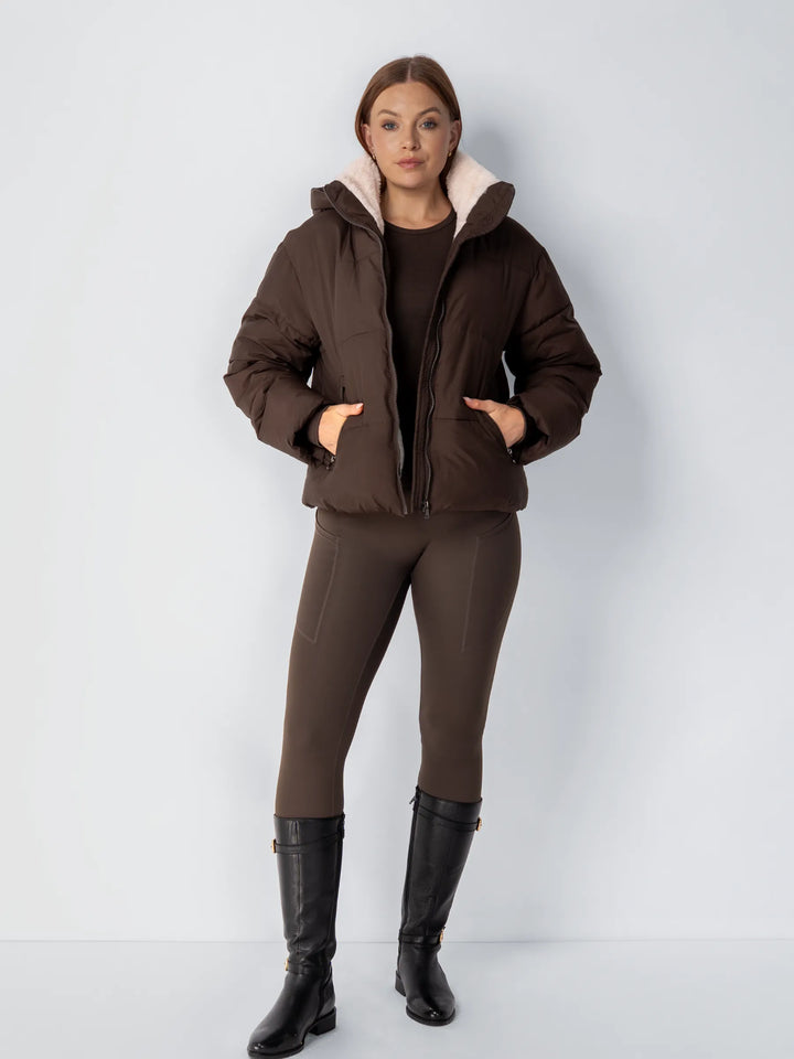 Ganzkörperansicht der braunen Steppjacke, offen getragen, mit braunen Leggings und schwarzen Reitstiefeln 15