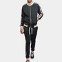 Mann in schwarzem Trainingsanzug mit Streifen, Reißverschlussjacke, Freizeithose, Sneakers.