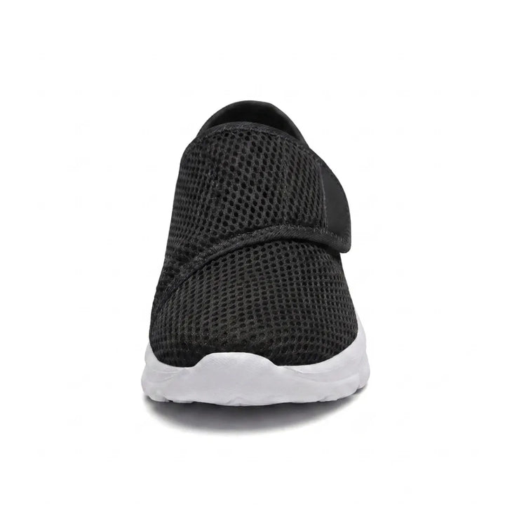 Schwarzer Mesh-Schuh mit Klettband und weißer Sohle in Frontansicht, die die breite, abgerundete Schuhspitze zeigt. 26
