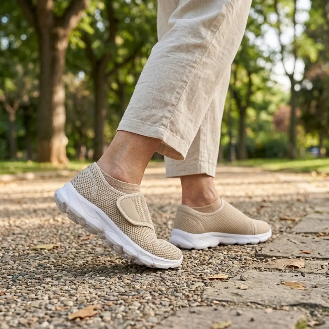 Person in hellen Leinenhosen läuft in beigen Klettschuhen mit weißer Sohle über einen Kiesweg in einem sonnigen Park. 29