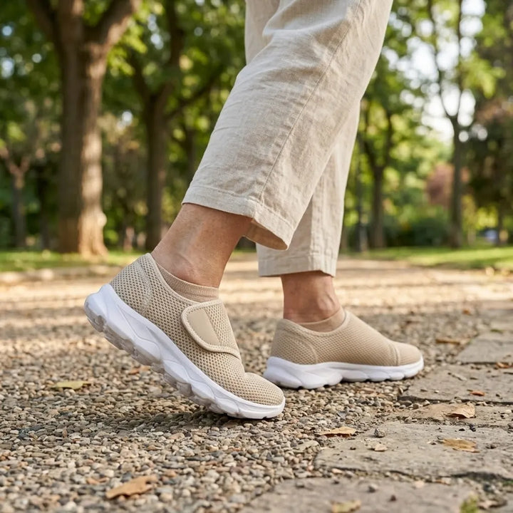 Person in hellen Leinenhosen läuft in beigen Klettschuhen mit weißer Sohle über einen Kiesweg in einem sonnigen Park. 29