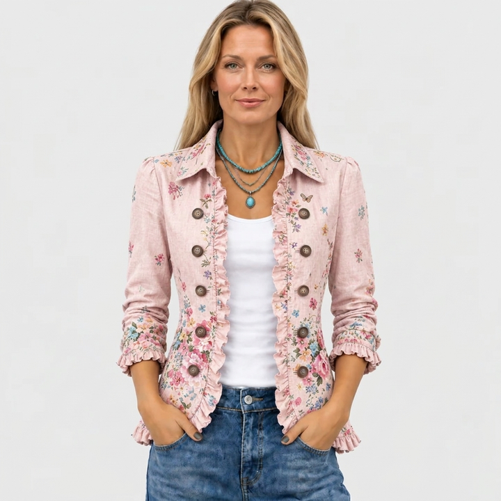 Frontansicht an einem Model: rosa Jacke mit Blumenmuster und Rüschen, offen über weißem Top, dazu Jeans und türkisfarbene Halsketten. 2
