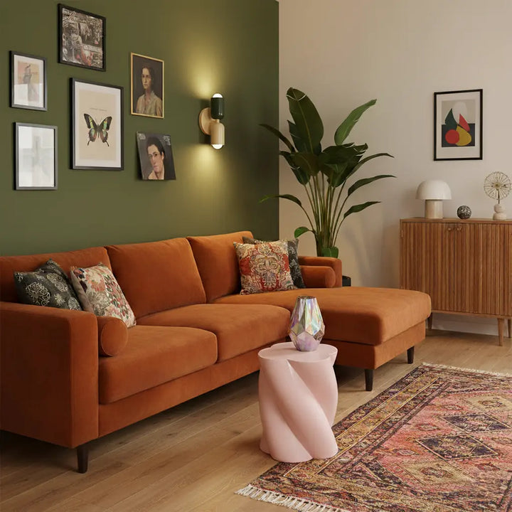 Wandlampe mit dunkelgrünem und cremefarbenem Schirm an einer grünen Wand über einem orangefarbenen Ecksofa mit gemustertem Teppich. 9