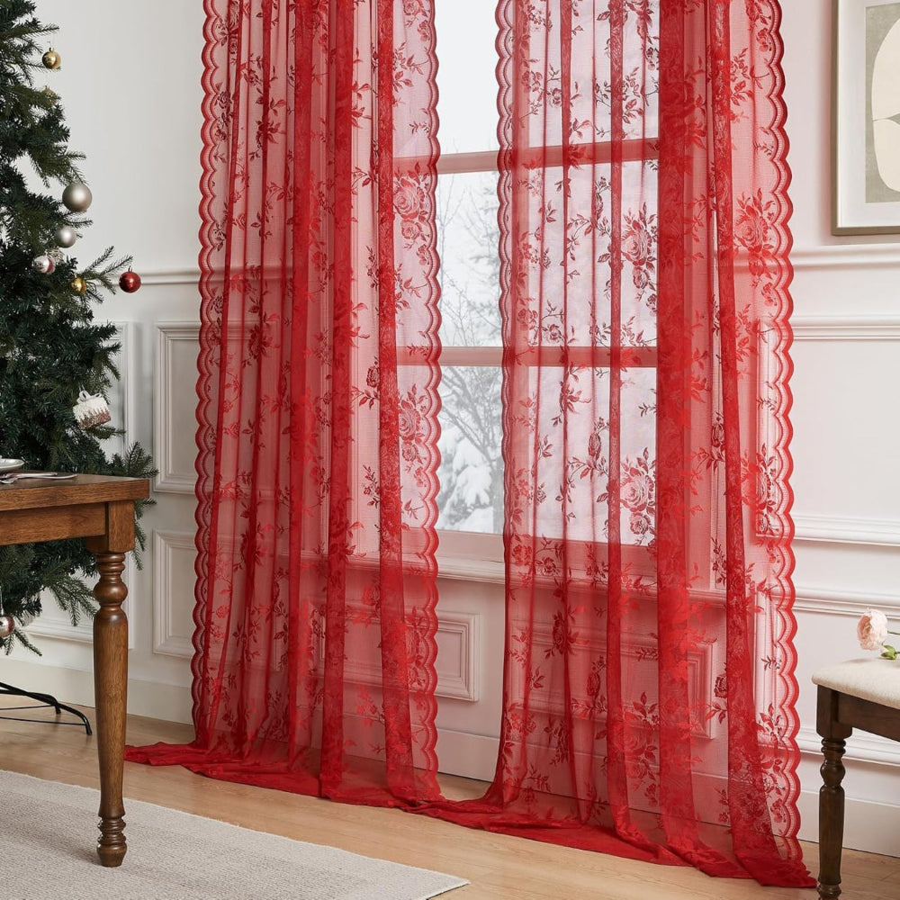 Zwei rote Spitzenpaneele mit Rosenmuster vor einem Fenster im weihnachtlich geschmückten Raum mit Tannenbaum und Holztisch. 7
