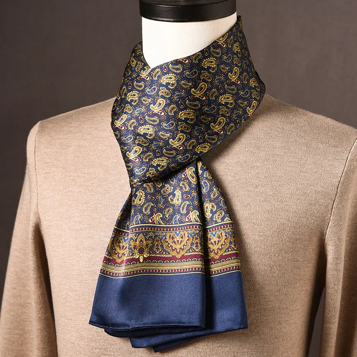 Blauer Seidenschal mit goldenem Paisleymuster und bordeauxfarbener Zierbordüre, an einer Büste über beigem Pullover getragen. 12