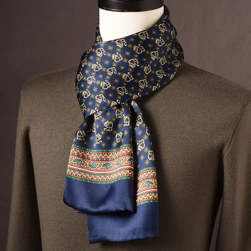 Marineblauer Seidenschal mit goldenen Motiven und bunter Paisley-Bordüre in Grün und Orange, über olivgrünem Pullover an einer Büste. 20