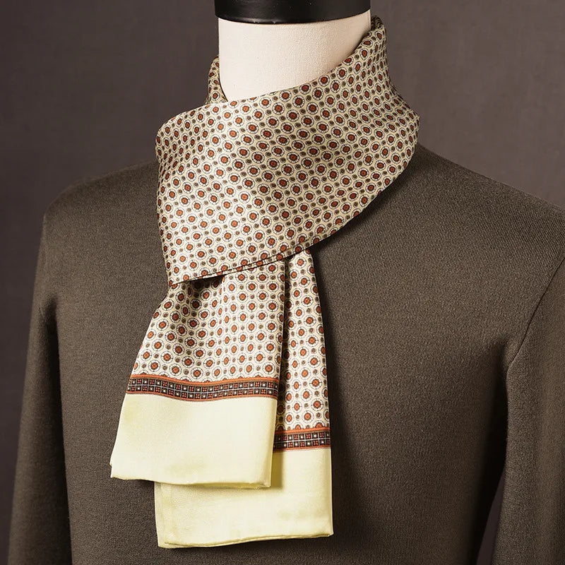 Heller Seidenschal mit orangebraunen Medaillonmotiven und hellgelbem Rand, über olivgrünem Pullover an einer Büste drapiert. 9