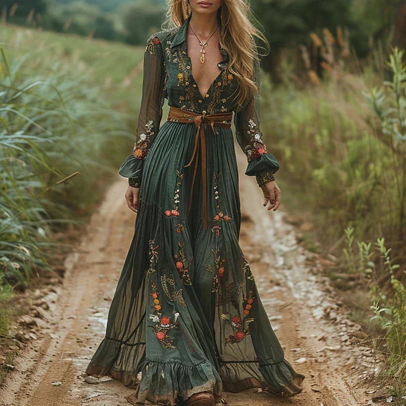 Model in dunkelgrünem Maxikleid mit Blumenstickerei und braunem Ledergürtel auf einem Feldweg, Ganzkörperansicht 1