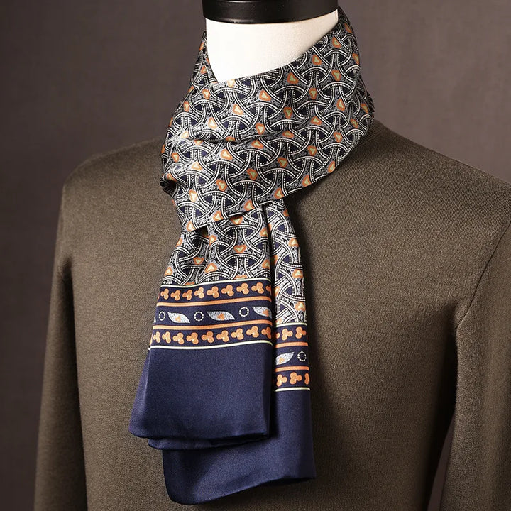 Seidenschal mit orange-grauem Bogenmuster auf dunklem Grund und marineblauem Rand mit Ornamentbordüre, über olivgrünem Pullover. 11