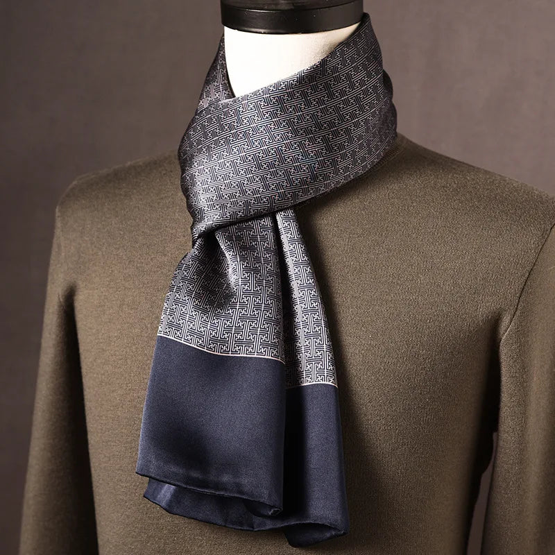 Grau-blauer Seidenschal mit geometrischem Mäandermuster und marineblauem Rand, an einer Büste über olivgrünem Pullover. 10