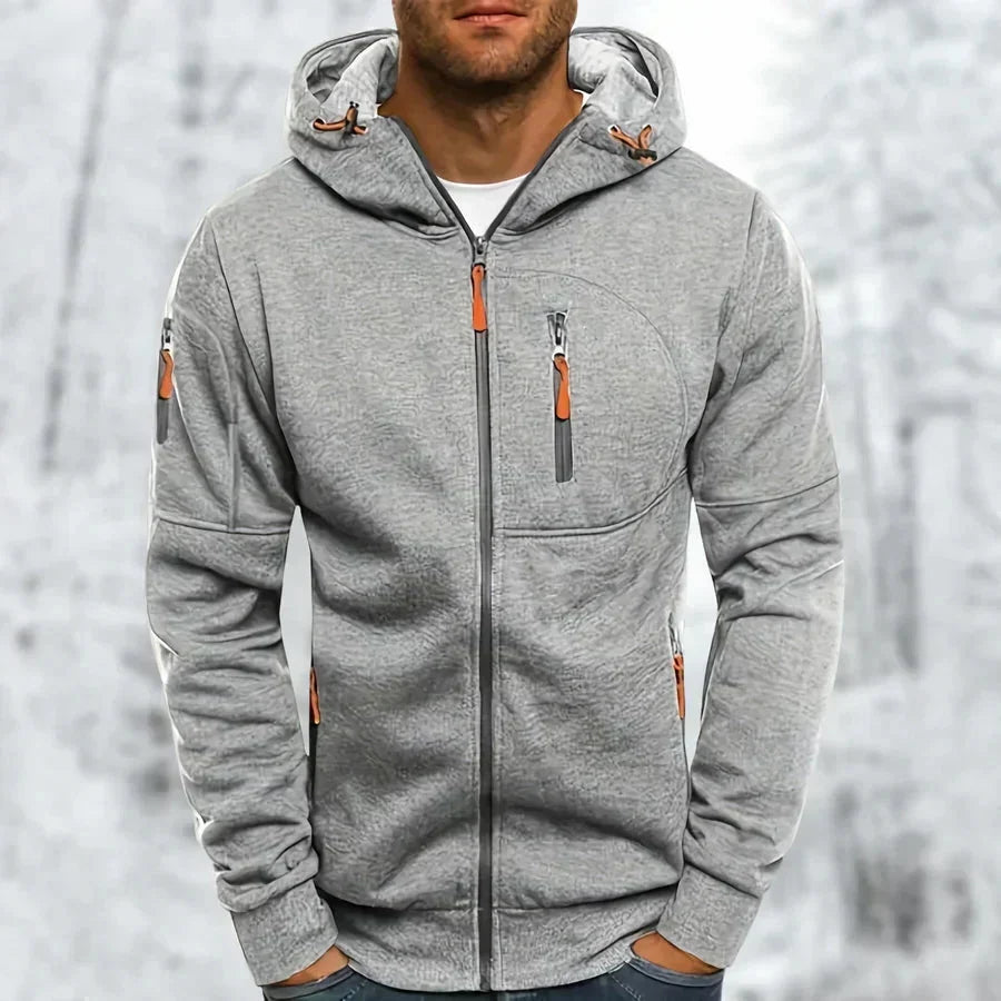 Hellgrauer, melierter Kapuzenpullover mit orangefarbenen Reißverschlussziehern und sichtbarer Jacquard-Struktur, von einem Mann getragen. 8