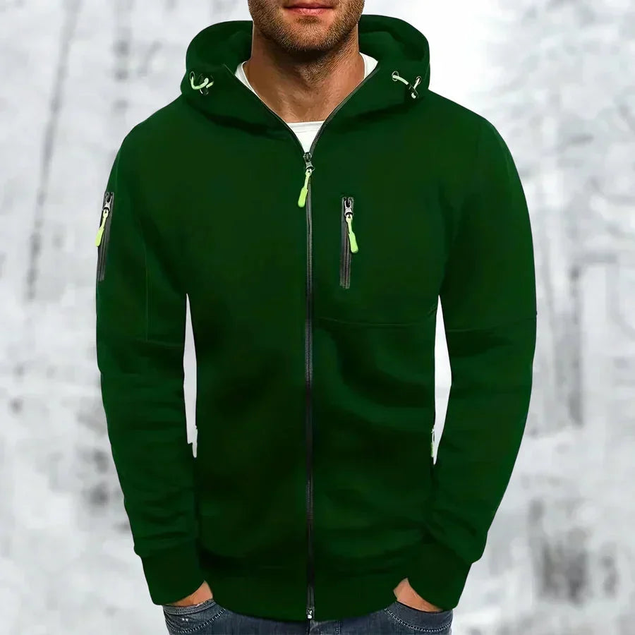 Kapuzenpullover in Dunkelgrün mit neongrünen Reißverschlussziehern und Kordelenden an der Kapuze, getragen von einem Mann im Schnee. 6