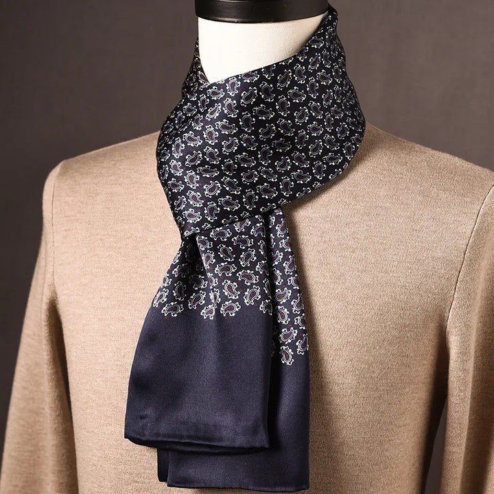 Dunkelblauer Seidenschal mit kleinen weißen Paisley-Motiven und glattem Abschluss, an einer Büste über beigem Pullover drapiert. 26