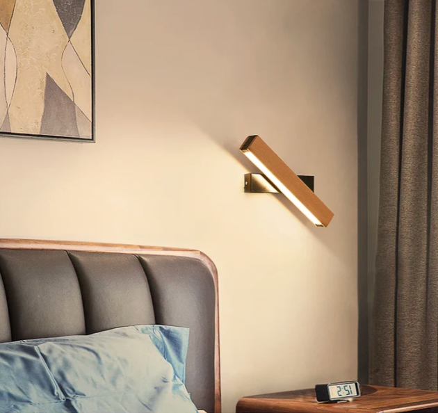 Schräg gedrehte Wandleuchte mit schwarzer Halterung über einem Polsterbett, daneben ein Vorhang, ein Bild und ein Wecker. 8